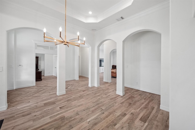 unfurnished dining area featuring light wood-style flooring, visible vents, a chandelier, crown molding, and arched walkways