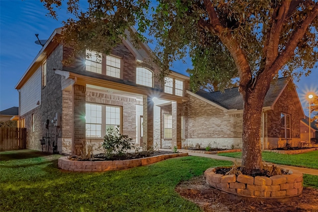view of front of property with brick siding, a front lawn, and fence