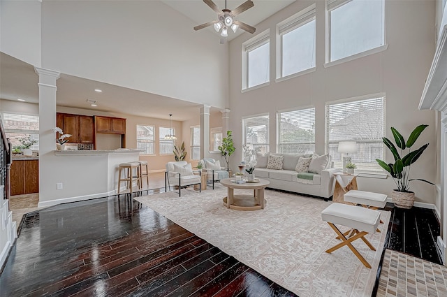 living area featuring a high ceiling, decorative columns, and hardwood / wood-style flooring