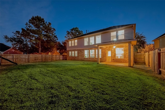 rear view of property featuring brick siding, a lawn, and a fenced backyard