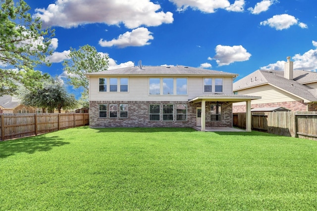 rear view of house with a fenced backyard, a patio, and a lawn