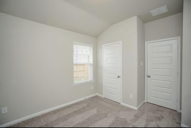 unfurnished bedroom with carpet floors, lofted ceiling, baseboards, and visible vents