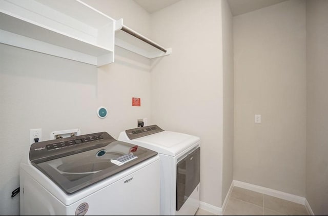 clothes washing area featuring laundry area, light tile patterned flooring, baseboards, and independent washer and dryer