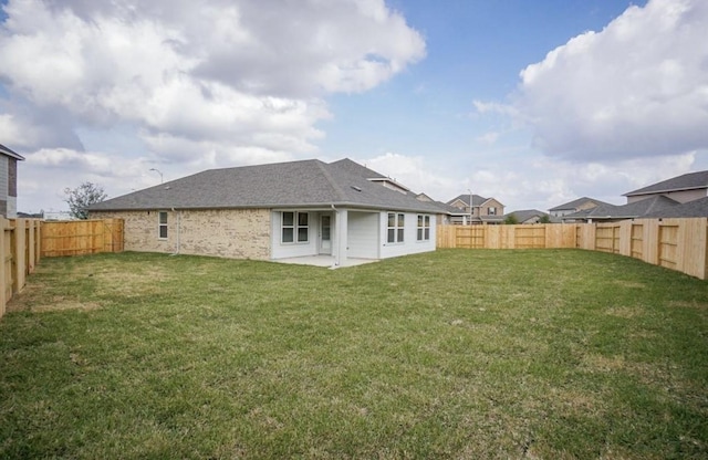 back of house with a patio, roof with shingles, a lawn, and a fenced backyard
