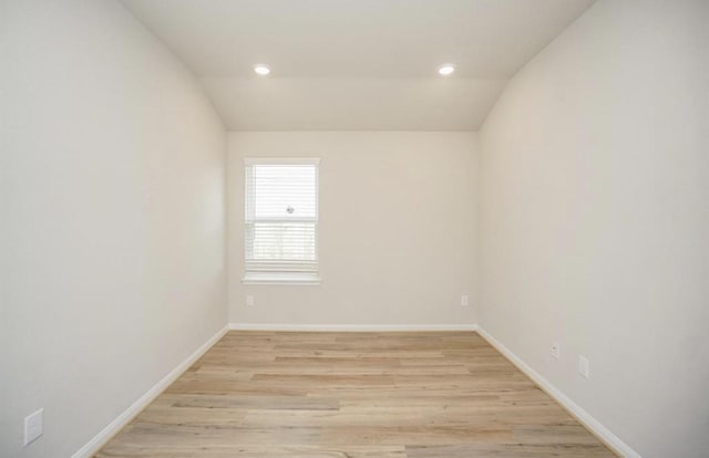 empty room featuring lofted ceiling, baseboards, light wood finished floors, and recessed lighting