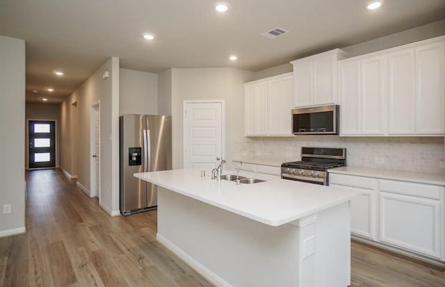 kitchen with visible vents, a sink, backsplash, stainless steel appliances, and an island with sink
