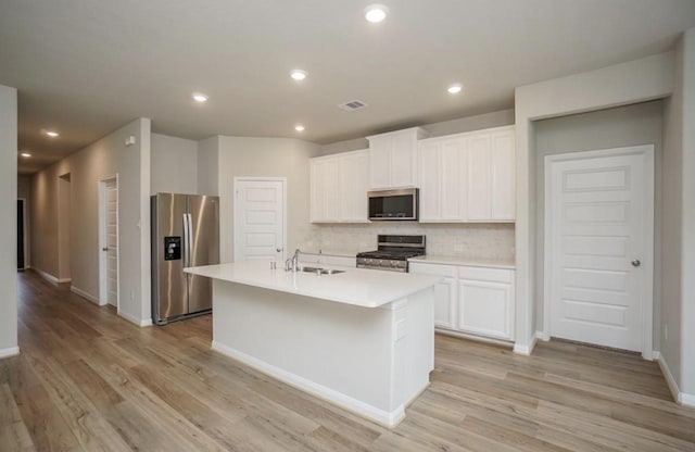 kitchen with stainless steel appliances, visible vents, light wood finished floors, backsplash, and light countertops