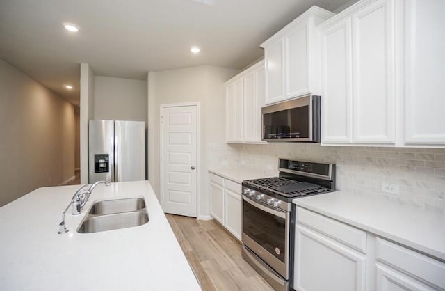 kitchen featuring backsplash, light wood-style floors, stainless steel appliances, and a sink