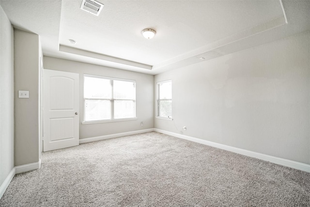 unfurnished room with a raised ceiling, carpet, baseboards, and visible vents