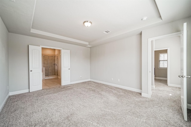 unfurnished bedroom featuring a tray ceiling, light carpet, baseboards, and visible vents