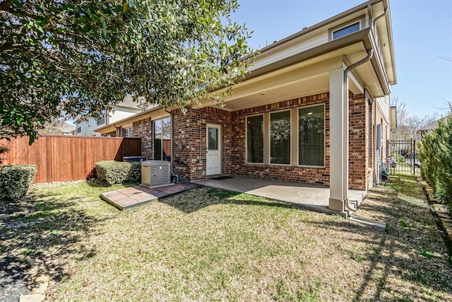 back of property with fence, brick siding, a patio, cooling unit, and a lawn