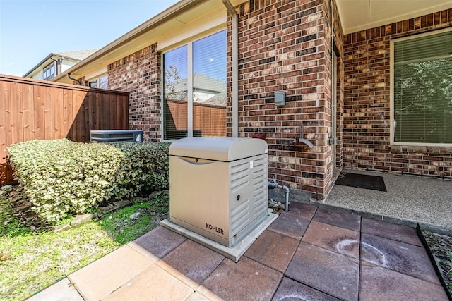 exterior details featuring fence, brick siding, and a power unit