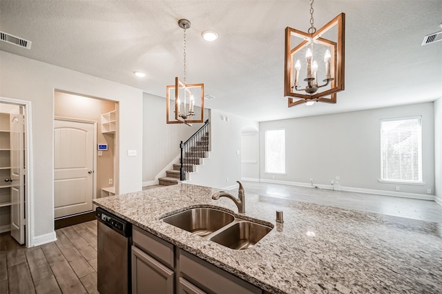 kitchen with a notable chandelier, decorative light fixtures, dishwasher, a sink, and open floor plan