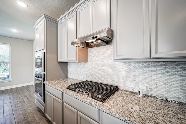 kitchen featuring dark wood finished floors, appliances with stainless steel finishes, exhaust hood, and backsplash