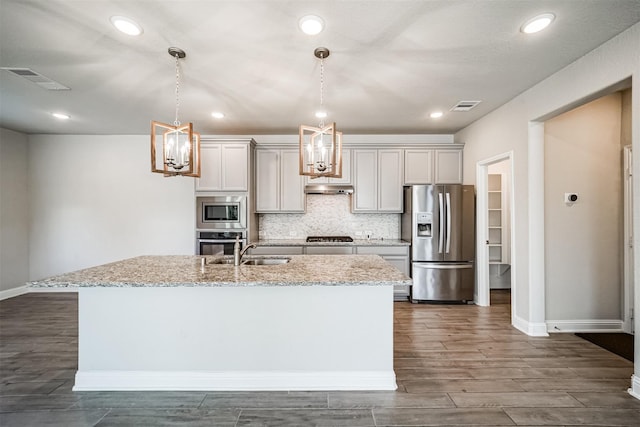 kitchen featuring a sink, visible vents, a center island with sink, dark wood-style flooring, and appliances with stainless steel finishes