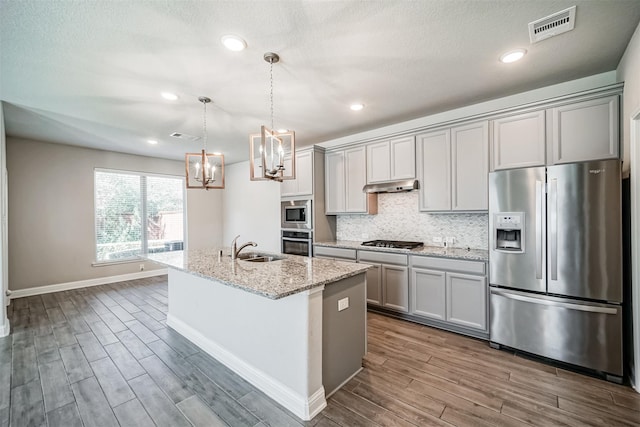 kitchen with wood finished floors, visible vents, under cabinet range hood, appliances with stainless steel finishes, and a chandelier