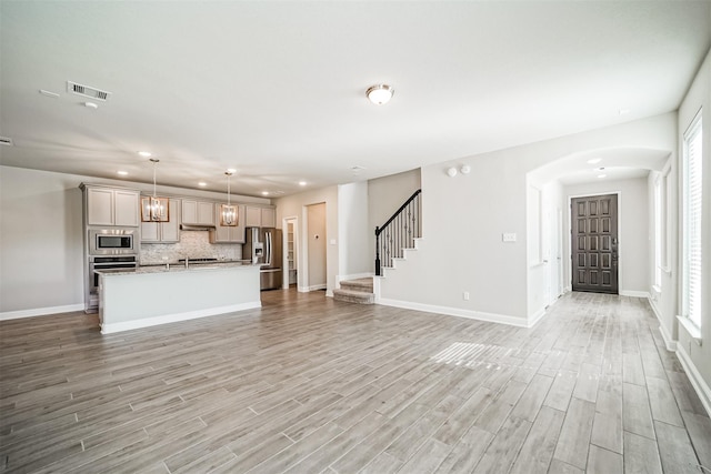 unfurnished living room with a healthy amount of sunlight, visible vents, recessed lighting, light wood finished floors, and baseboards
