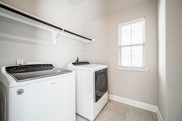 laundry area featuring washing machine and clothes dryer, baseboards, a healthy amount of sunlight, and laundry area