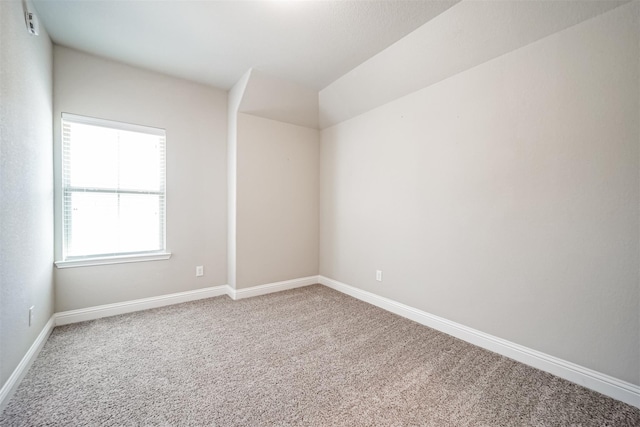 carpeted spare room featuring baseboards