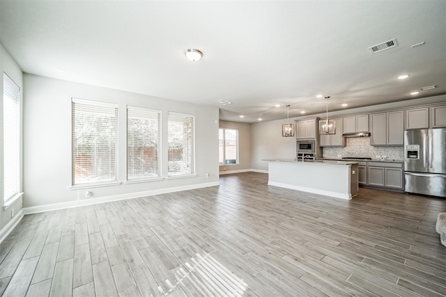 unfurnished living room with visible vents, wood finished floors, baseboards, and recessed lighting