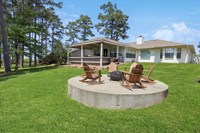 rear view of house featuring a patio area, a fire pit, a chimney, and a lawn