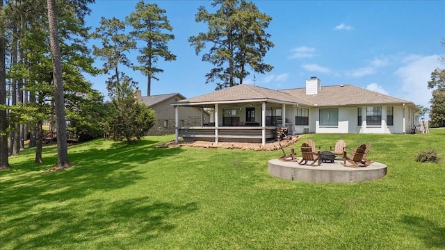 rear view of house with an outdoor fire pit, a yard, a patio area, and a chimney