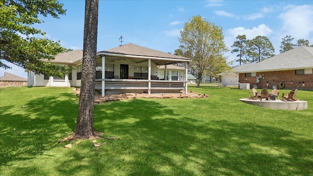 back of house with a yard and a fire pit