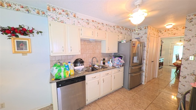 kitchen featuring light tile patterned floors, wallpapered walls, appliances with stainless steel finishes, and a sink