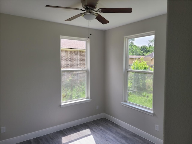 empty room featuring plenty of natural light, dark wood-type flooring, and baseboards