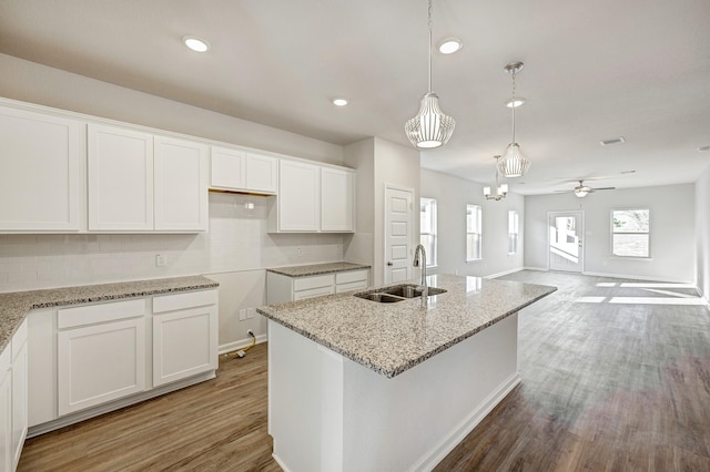 805 Apple Blossom Dr, La Marque, TX 77568 - kitchen with light stone countertops, light wood-style flooring, tasteful backsplash, a sink, and white cabinets