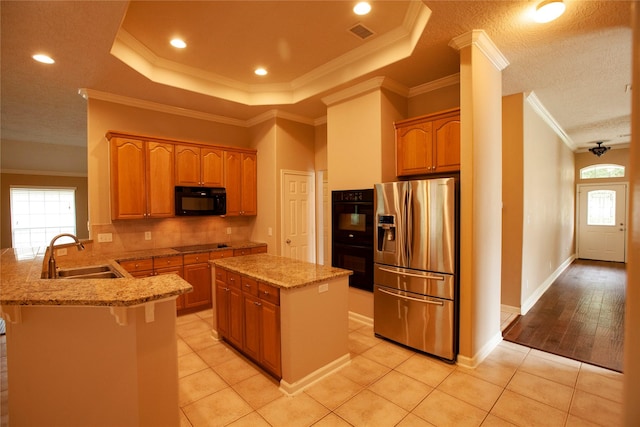 13847 Ventura Rd, Willis, TX 77318 - kitchen featuring a sink, a peninsula, tasteful backsplash, black appliances, and light stone countertops