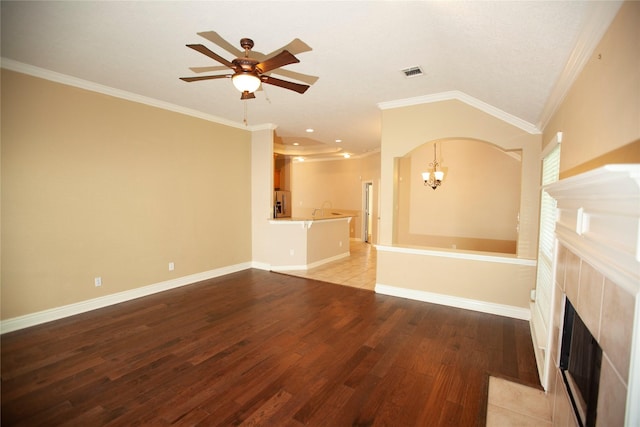 13847 Ventura Rd, Willis, TX 77318 - unfurnished living room featuring ceiling fan with notable chandelier, light wood-type flooring, visible vents, a fireplace, and crown molding