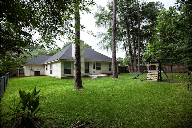 13847 Ventura Rd, Willis, TX 77318 - rear view of house with a yard, a chimney, a fenced backyard, central air condition unit, and a playground