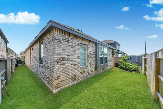 view of side of home featuring a yard, central AC unit, brick siding, and a fenced backyard