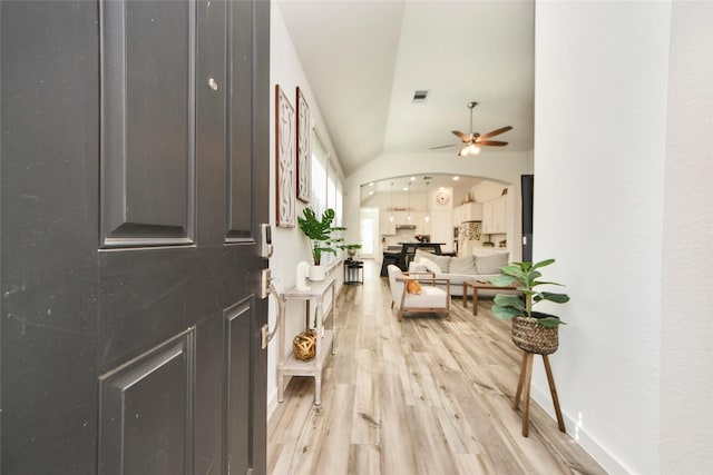 foyer entrance with light wood-style flooring, arched walkways, a ceiling fan, and visible vents
