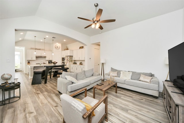 living room featuring a ceiling fan, light wood-type flooring, arched walkways, vaulted ceiling, and recessed lighting