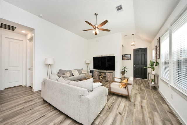 living room with lofted ceiling, ceiling fan, light wood finished floors, and visible vents