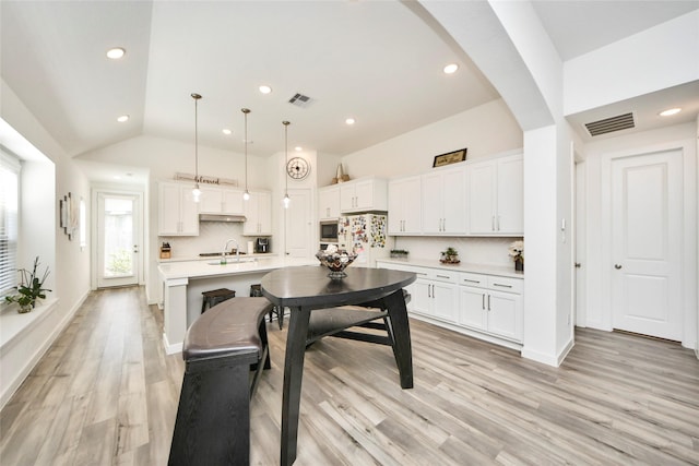 kitchen featuring backsplash, light countertops, white cabinets, and visible vents