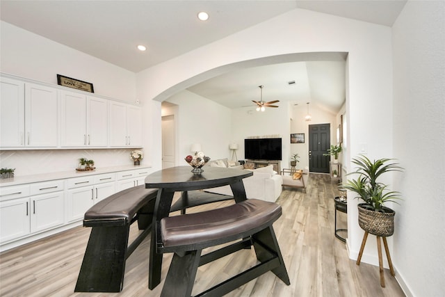 dining area with light wood finished floors, a ceiling fan, arched walkways, lofted ceiling, and recessed lighting