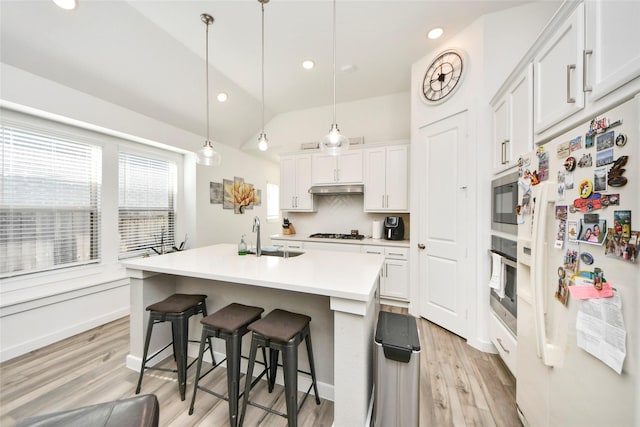 kitchen with light wood finished floors, white cabinetry, stainless steel appliances, and a kitchen breakfast bar