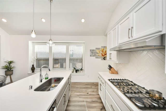 kitchen featuring under cabinet range hood, recessed lighting, stainless steel gas stovetop, and a sink