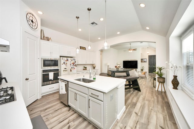 kitchen with a ceiling fan, a sink, stainless steel appliances, light wood-style floors, and vaulted ceiling