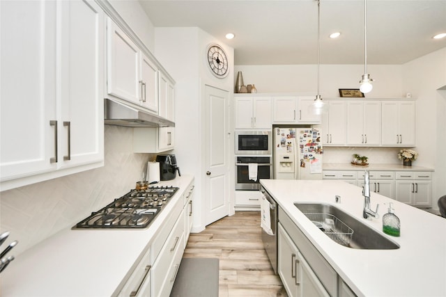 kitchen with a sink, stainless steel appliances, white cabinets, backsplash, and under cabinet range hood