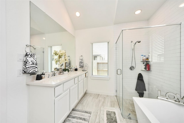 bathroom featuring double vanity, a stall shower, a sink, a soaking tub, and recessed lighting
