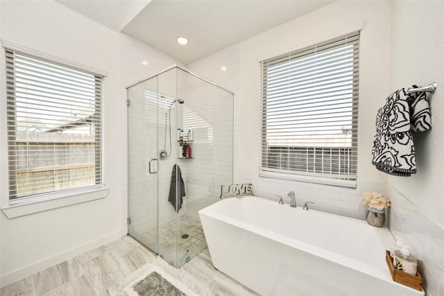 full bath featuring a freestanding bath, a shower stall, and a healthy amount of sunlight