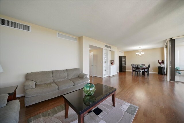 living room featuring a chandelier, dark wood-style floors, baseboards, and built in features