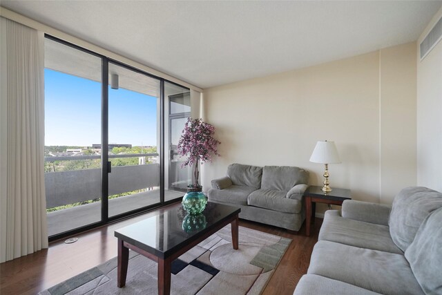 living room featuring a wall of windows, visible vents, and wood finished floors