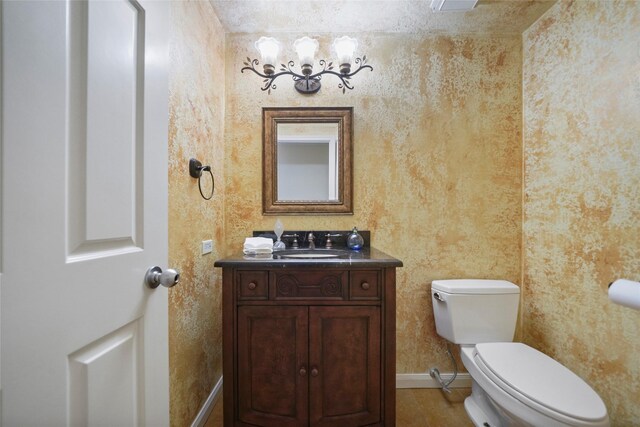 bathroom with a chandelier, vanity, toilet, and baseboards