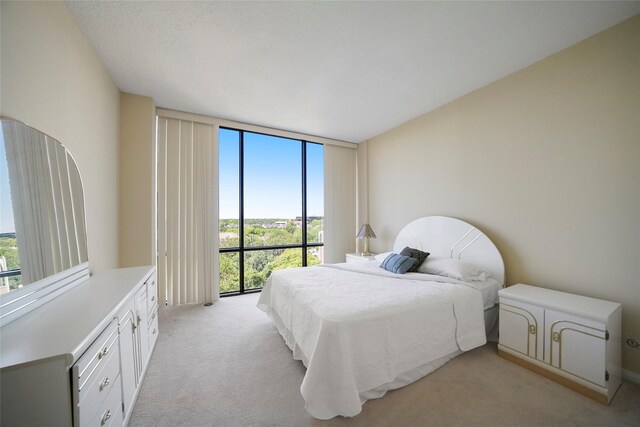 bedroom with multiple windows, a wall of windows, and light colored carpet