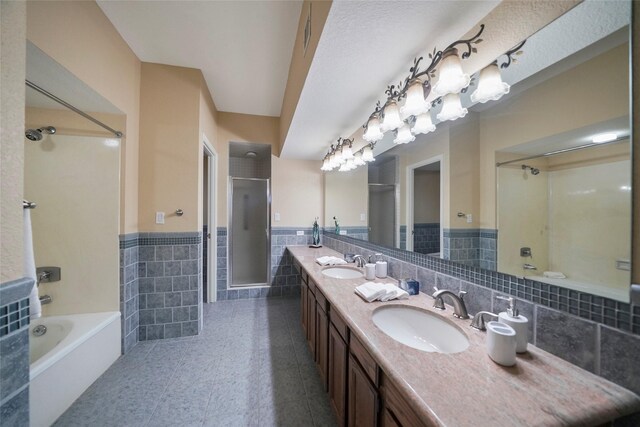 bathroom with tile walls, an enclosed shower, wainscoting, a tub, and double vanity
